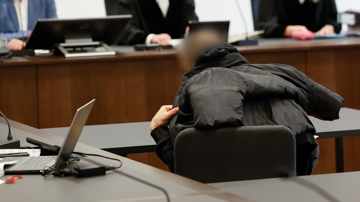Angeklagter sitzt mit Jacke halb über den Kopf gezogen vor Gericht