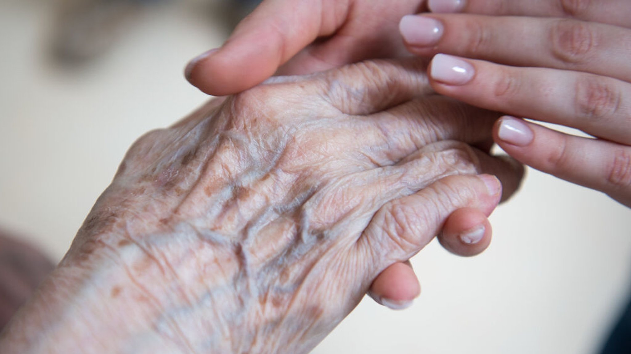 ARCHIV - 29.03.2018, Brandenburg, Velten: Eine Pflegerin hält die Hand einer Bewohnerin im Seniorenzentrum Sankt Elisabeth. Patientenschützer fordern mehr Hilfen für Ältere mit Depressionen. Foto: Christophe Gateau/dpa +++ dpa-Bildfunk +++