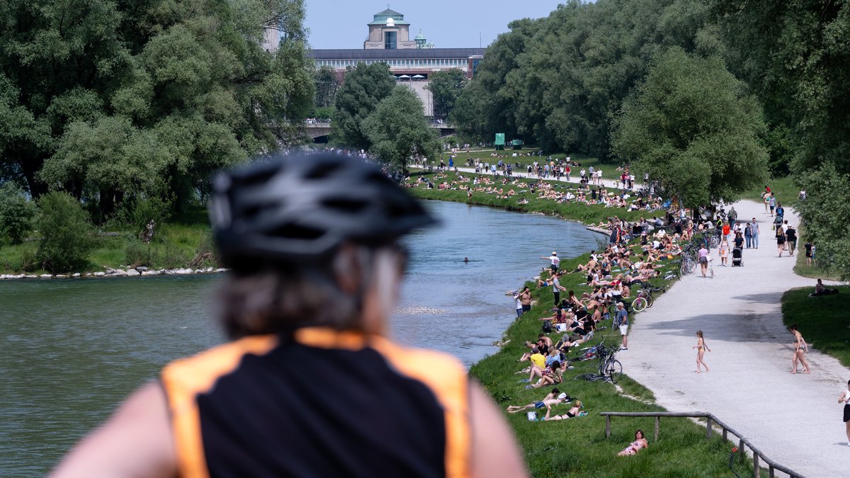 Zahlreiche Menschen genießen sommerliches Wetter am Ufer der Isar in der Münchner Innenstadt.