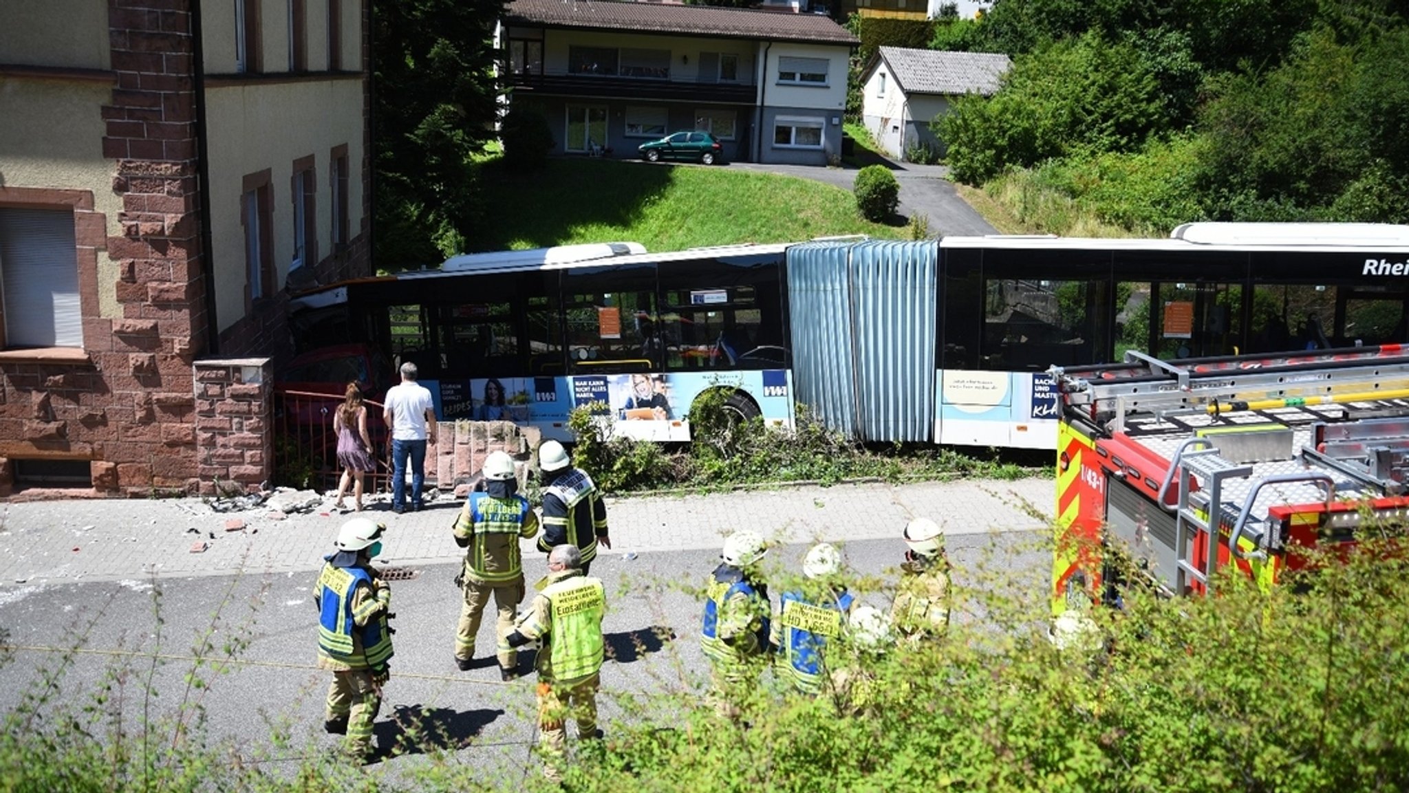 Heidelberg: Einsatzkräfte begutachten eine Unfallstelle, an der ein Linienbus gegen ein Wohnhaus gefahren ist.