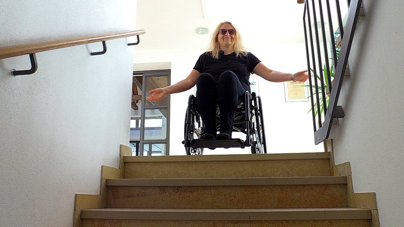 Kerstin Rathgeb im Rollstuhl an einem Treppenabsatz.