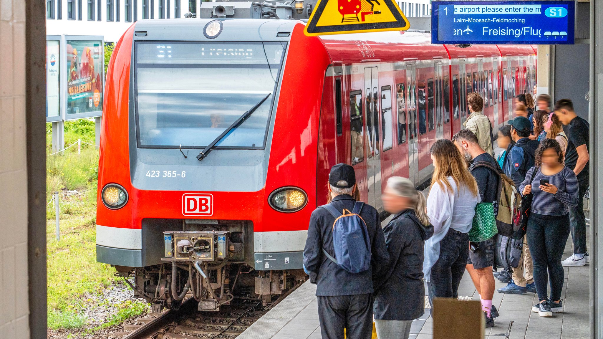 Flughafen S-Bahn S1 bei der Einfahrt im S-Bahnhof Donnersbergerbrücke, Fahrgäste warten am Bahnsteig.