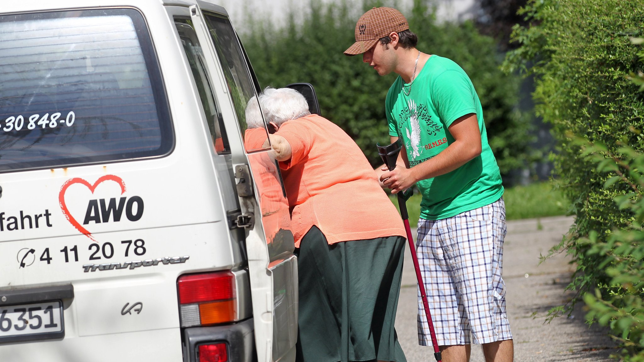 Ein Zivildienstleistender hilft als Fahrdienst einer Seniorin in einen Kleinbus der Arbeiterwohlfahrt