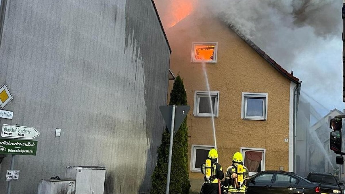 Feuerwehrleute löschen bis in den Dachstuhl eines vom Großbrand betroffenen Hauses in Hofkirchen