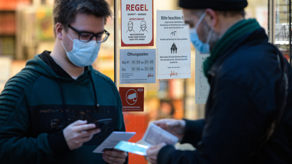 Der Mitarbeiter eines Buchladens in Leipzig überprüft den 2G-Nachweis eines Kunden am 22. November 2021.