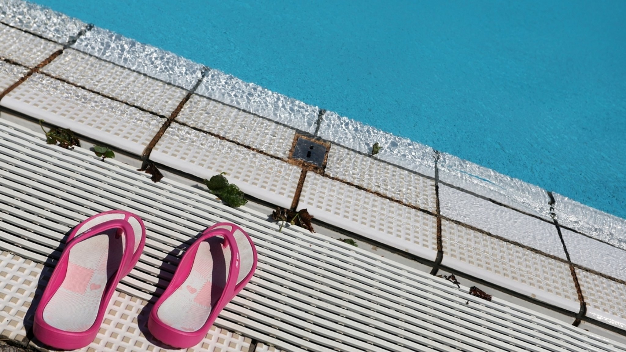 Symbolbild: Badeschuhe am Rande eines Schwimmbeckens
