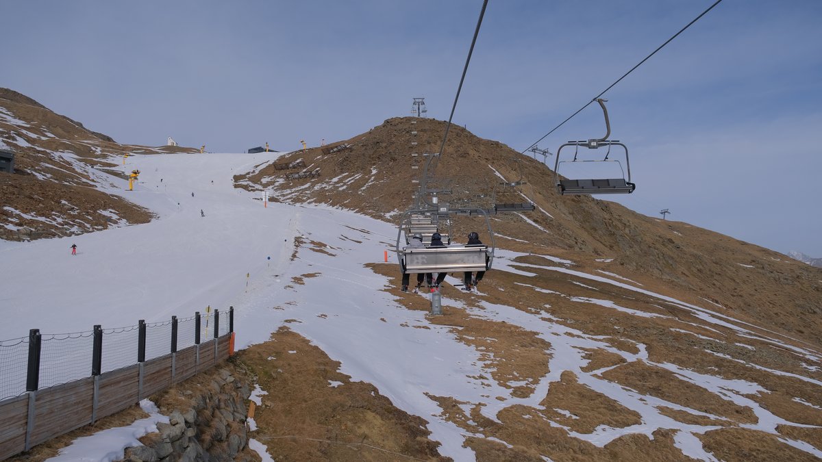 Ein Lift fährt über braune Hügel. Daneben eine weiße Skipiste. | Bild: Selina Oberpriller Ein Lift fährt über braune Hügel. Daneben eine weiße Skipiste.