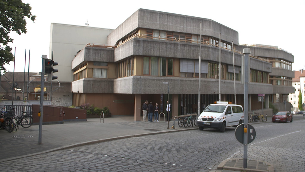 Ein Schulgebäude aus grauem Beton an einer gepflasterten Straße.