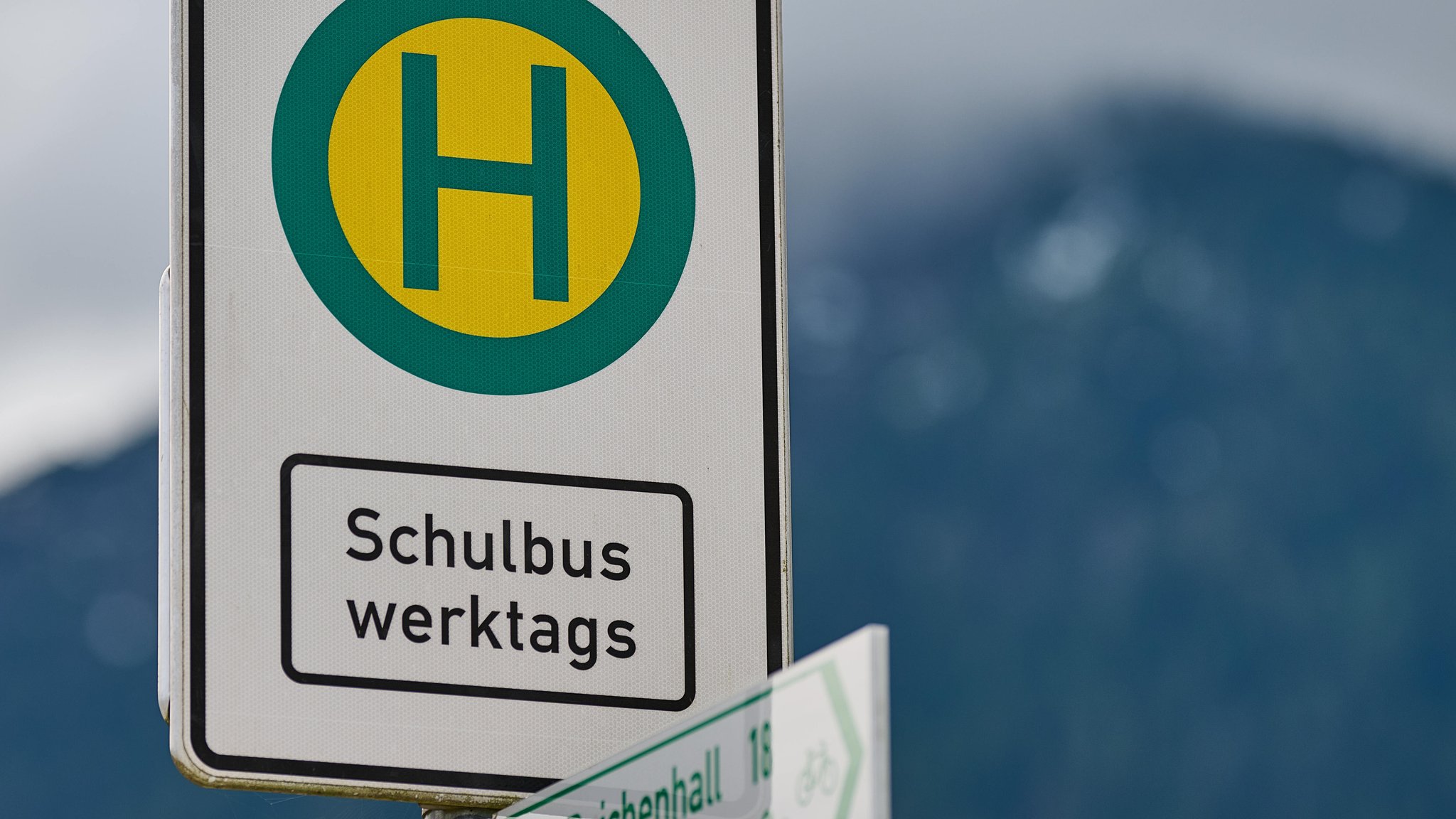 Ein Haltestellenschild, an dem Kinder auf dem Bus warten. 
