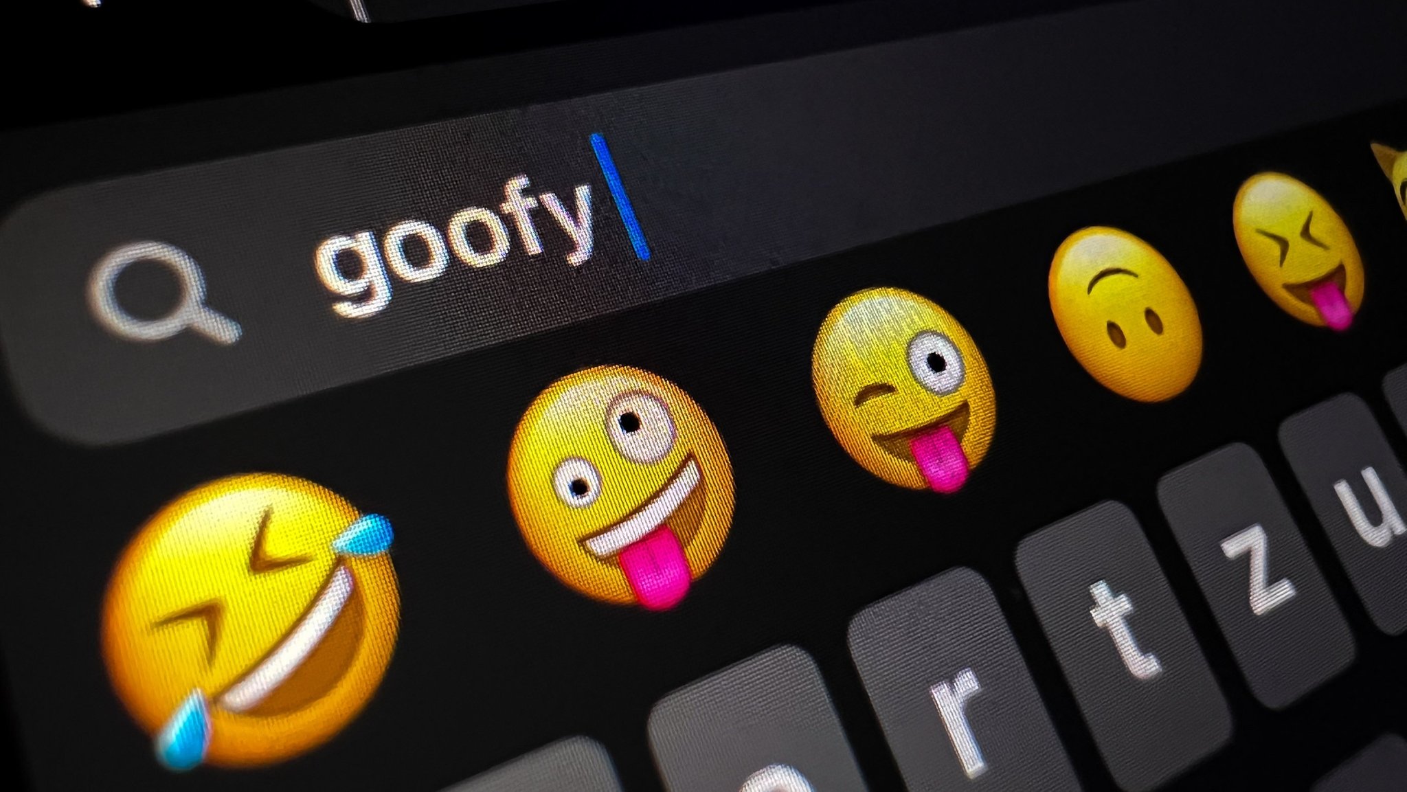 Auf einem Bildschirm ist "Goofy" zu lesen - das Jugendwort des Jahres 2023, daneben Smileys..