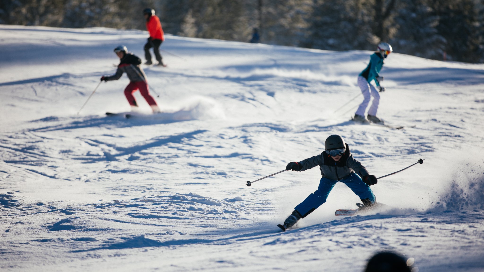 Kinder und Teenager auf einer Skipiste.