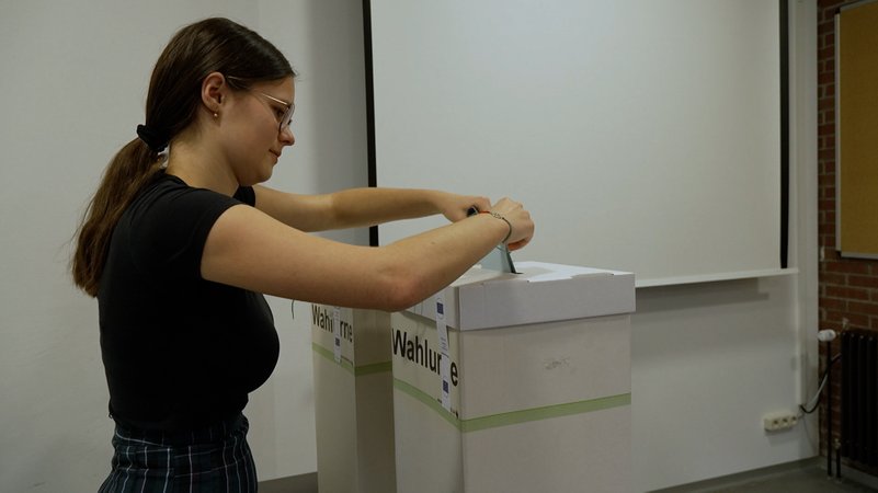 Eine Schülerin wirft ihren Wahlzettel in die Wahlurne ein. 