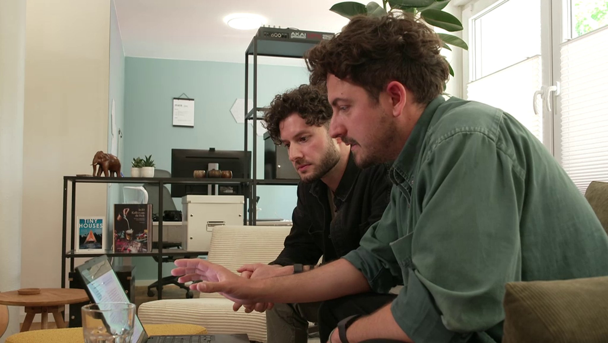 Zwei junge Männer sitzen vor einem Laptop und schauen auf den Bildschirm
