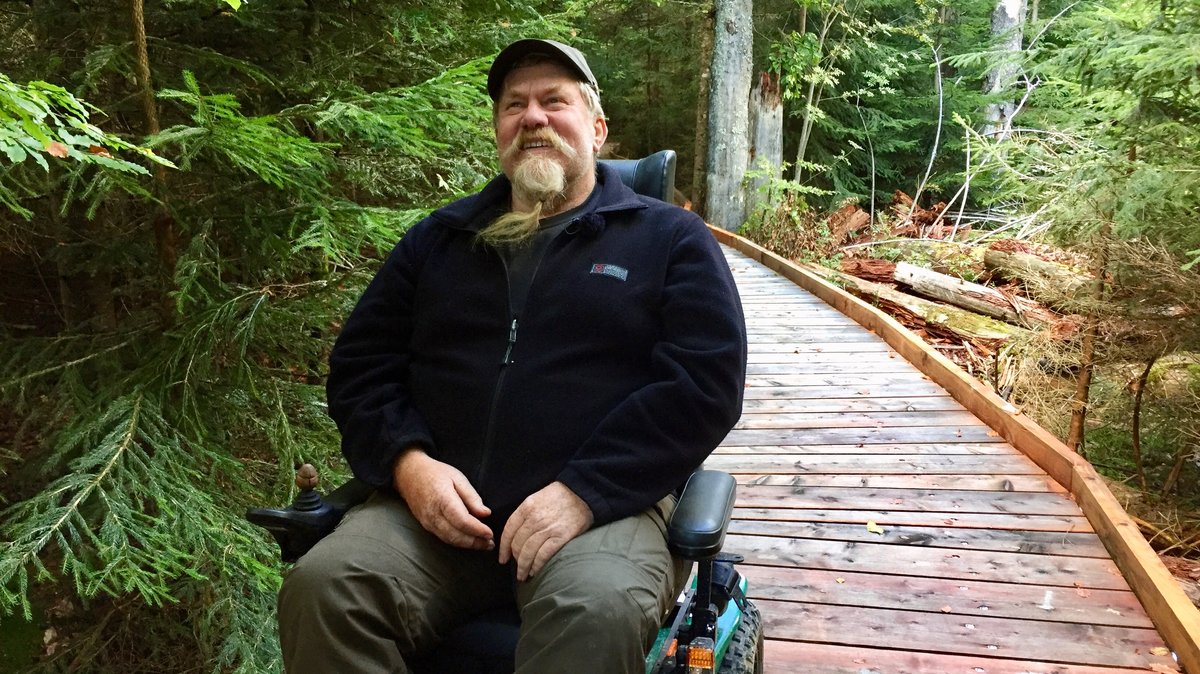 Ein Mann in einem Elektro-Rollstuhl im Wald