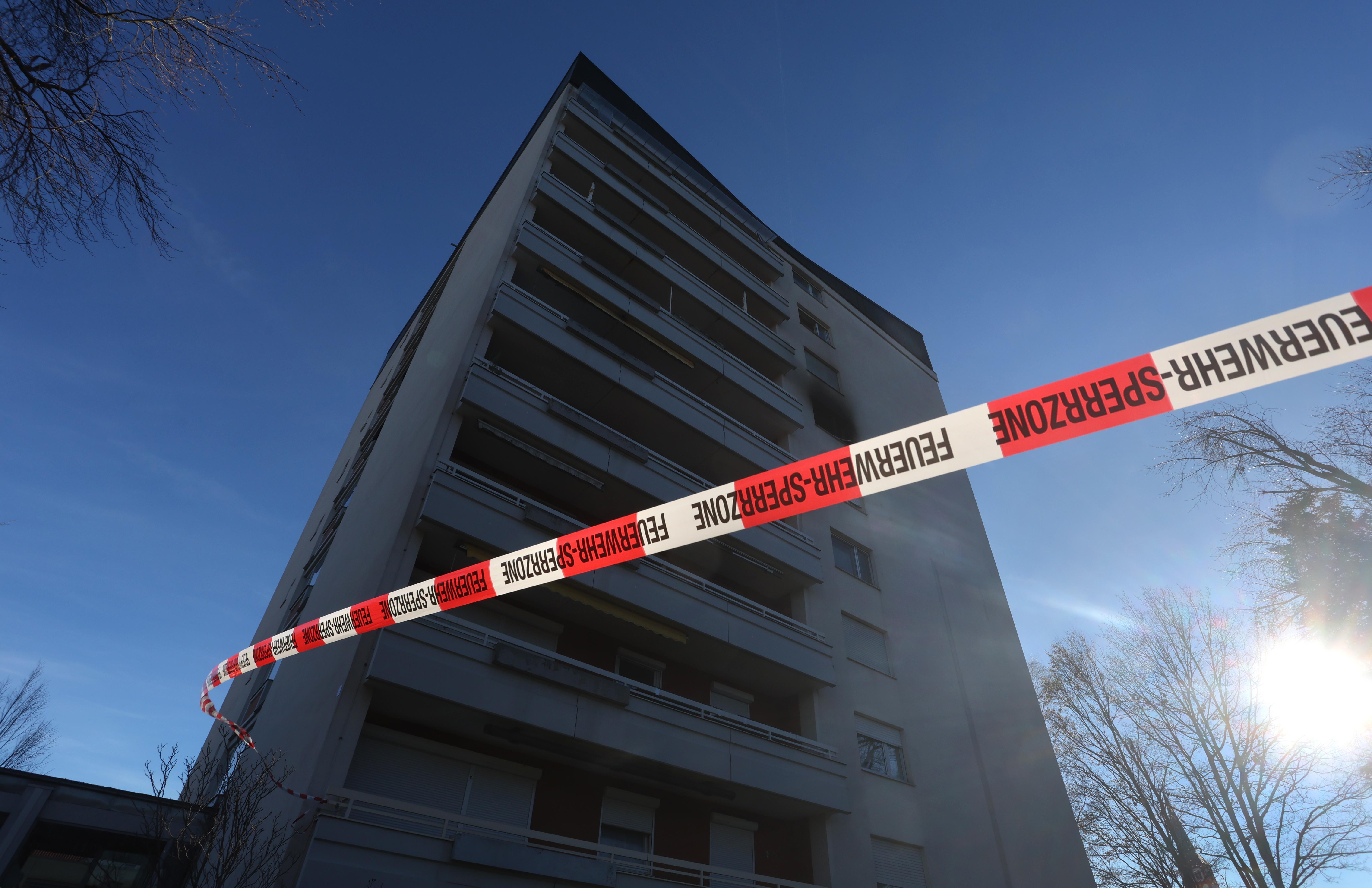 Ein Absperrband der Feuerwehr vor einem Mehrfamilienhaus 