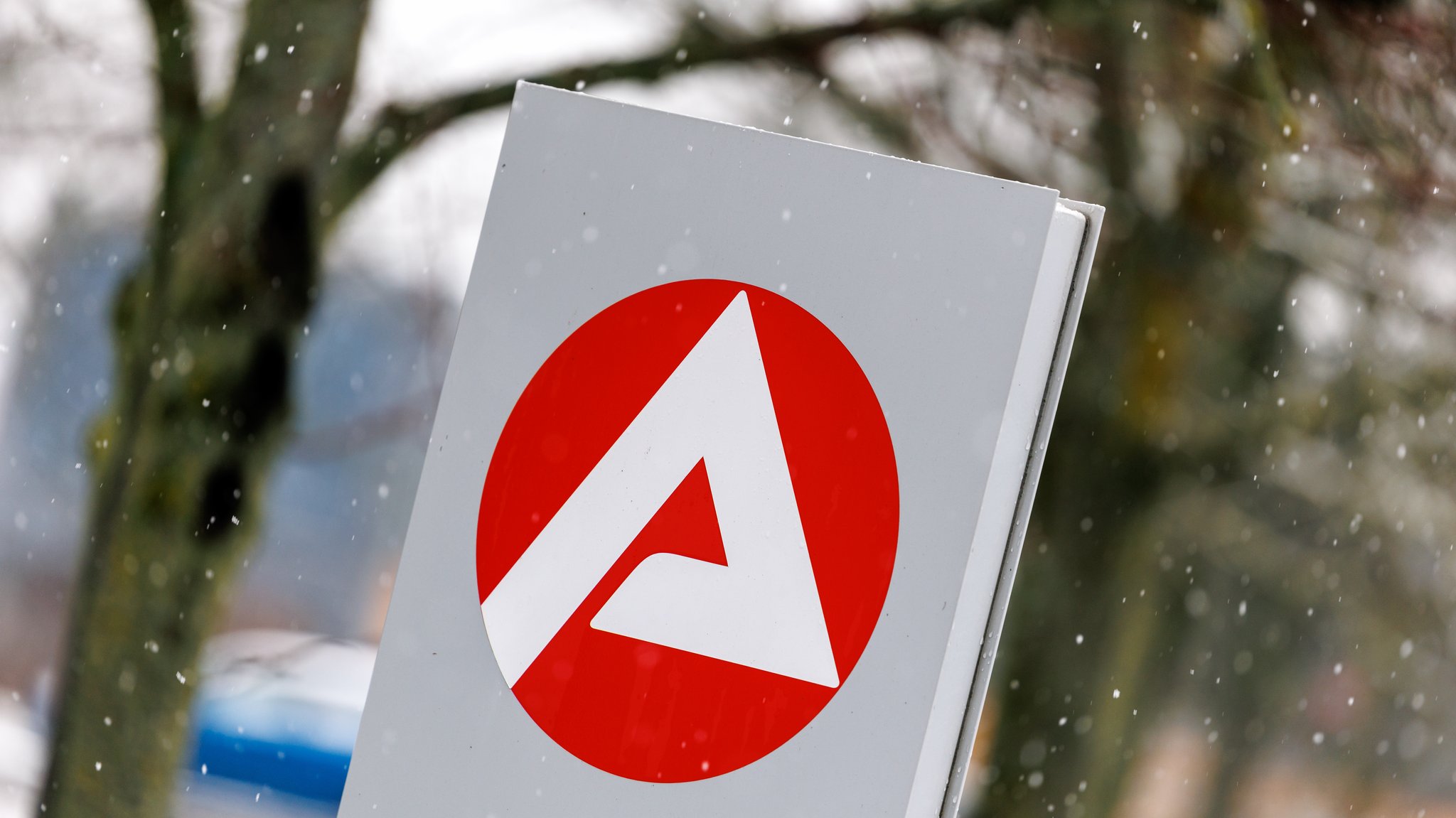 Das Logo der Agentur für Arbeit ist am 02.01.2025 an einer Stele vor dem Behördengebäude der Agentur für Arbeit in Hof (Bayern) im Schnee zu sehen.