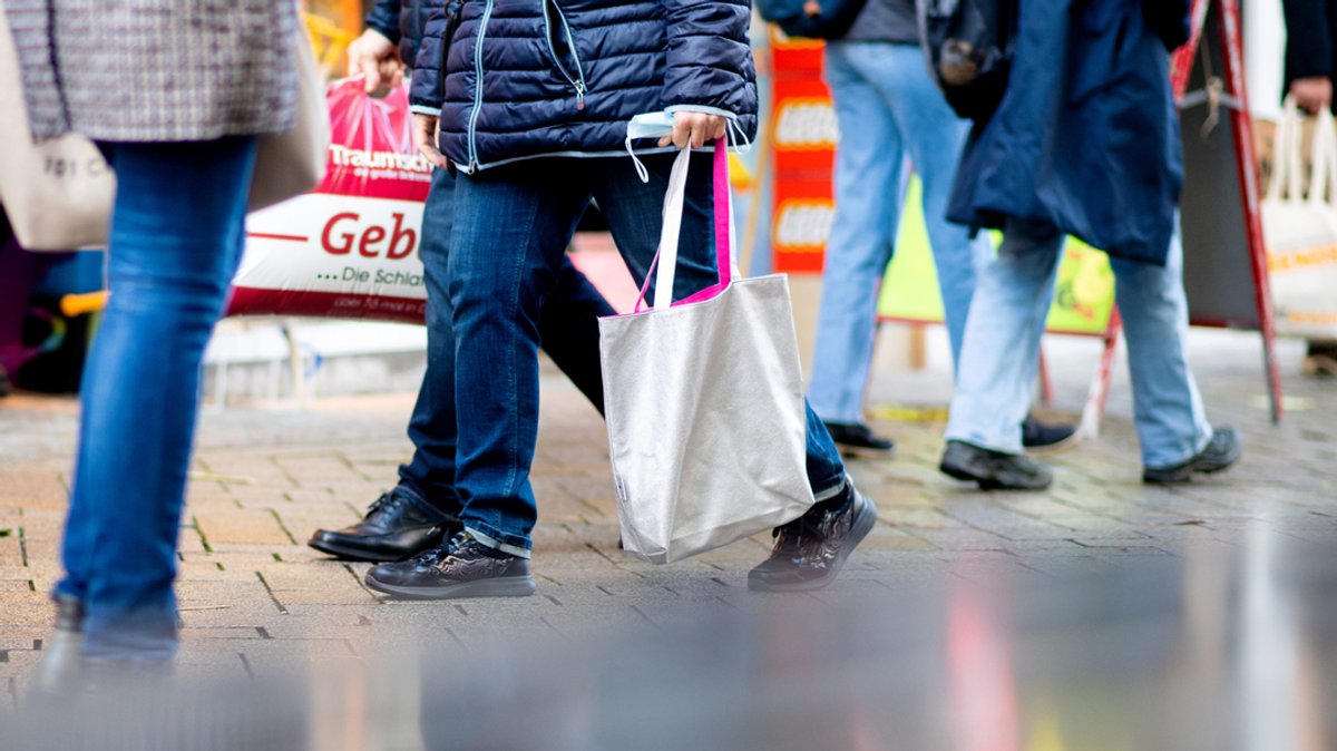 Menschen gehen mit Einkaufstaschen durch eine Fußgängerzone. (Symbolbild)