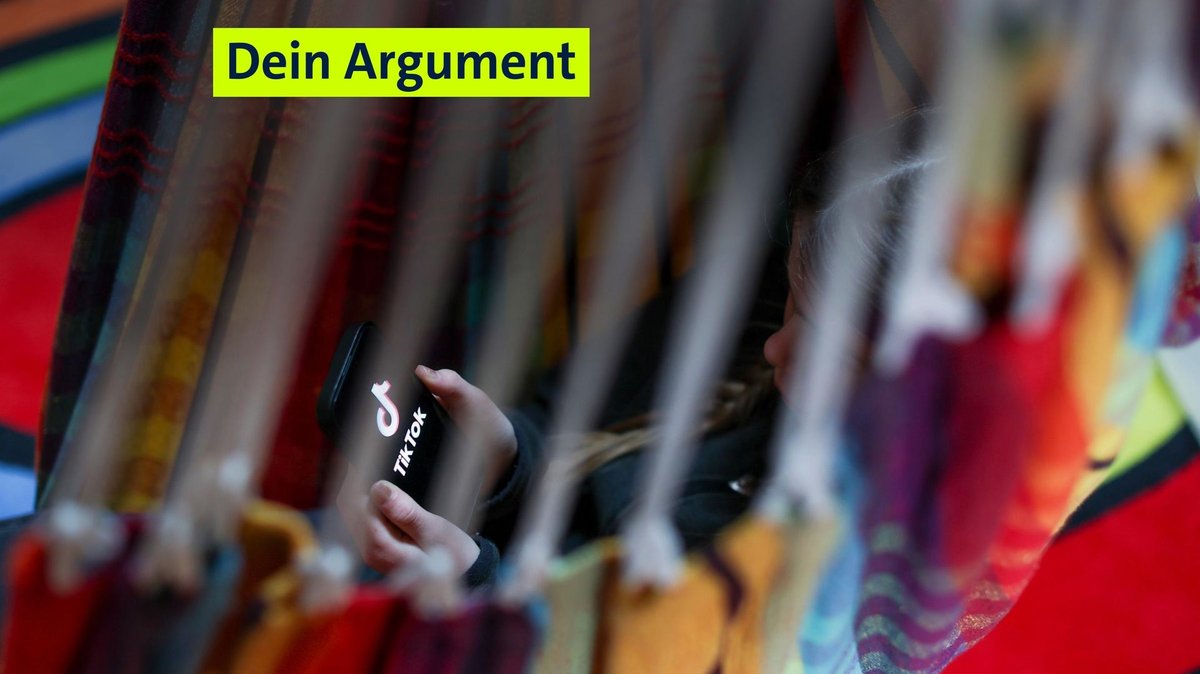 Ein Kind liegt mit dem Handy in der Hand in einer Hängematte. Auf dem Handy ist die App "Tiktok" offen. 