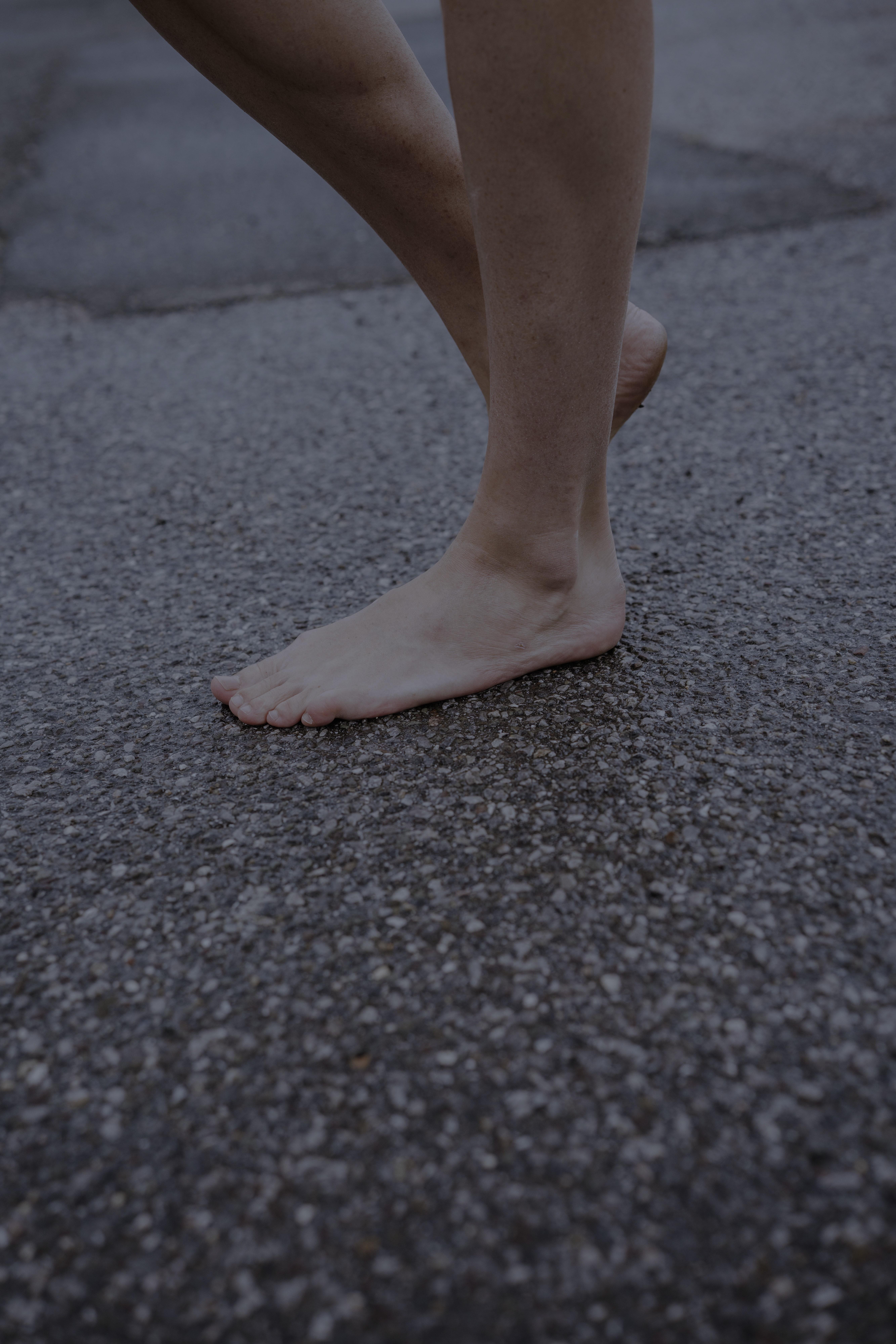 Nackte Füße auf einer Teerstraße.