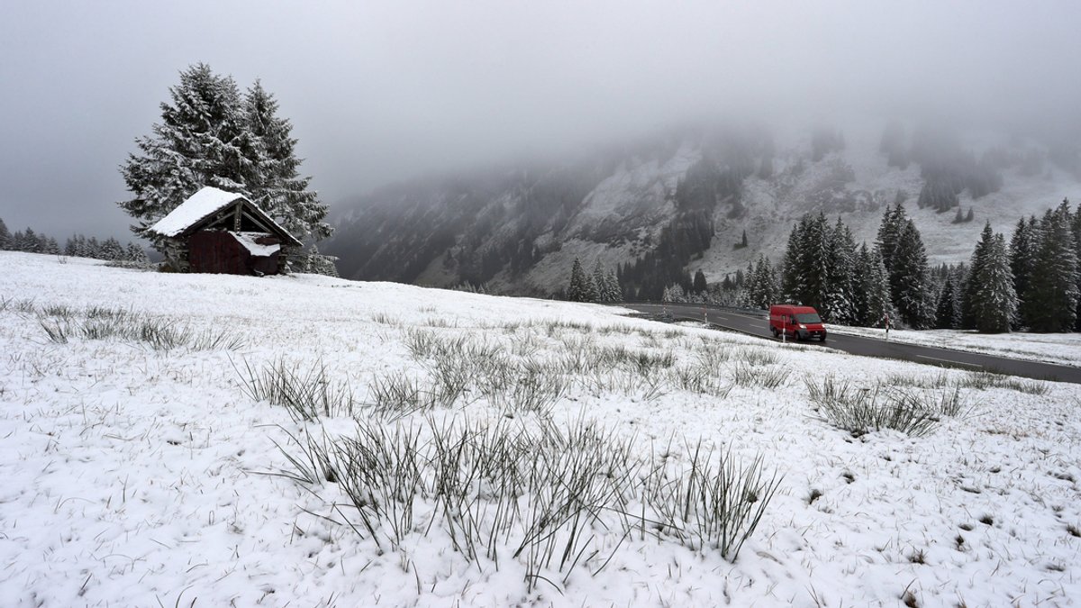 05.11.2022, Bayern, Obermaiselstein: Ein Auto fährt am Riedbergpass durch die mit Neuschnee bedeckte Landschaft. 