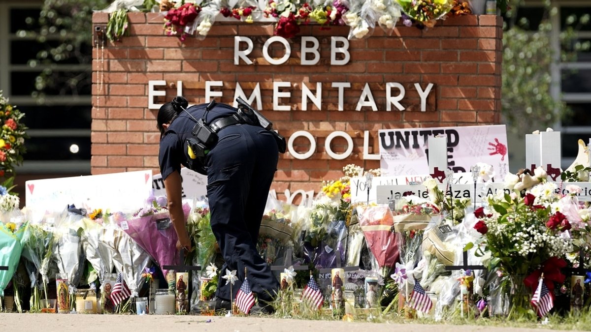 ARCHIV - 27.05.2022, USA, Uvalde: Eine Polizistin legt Blumen vor der Robb Elementary School nieder.