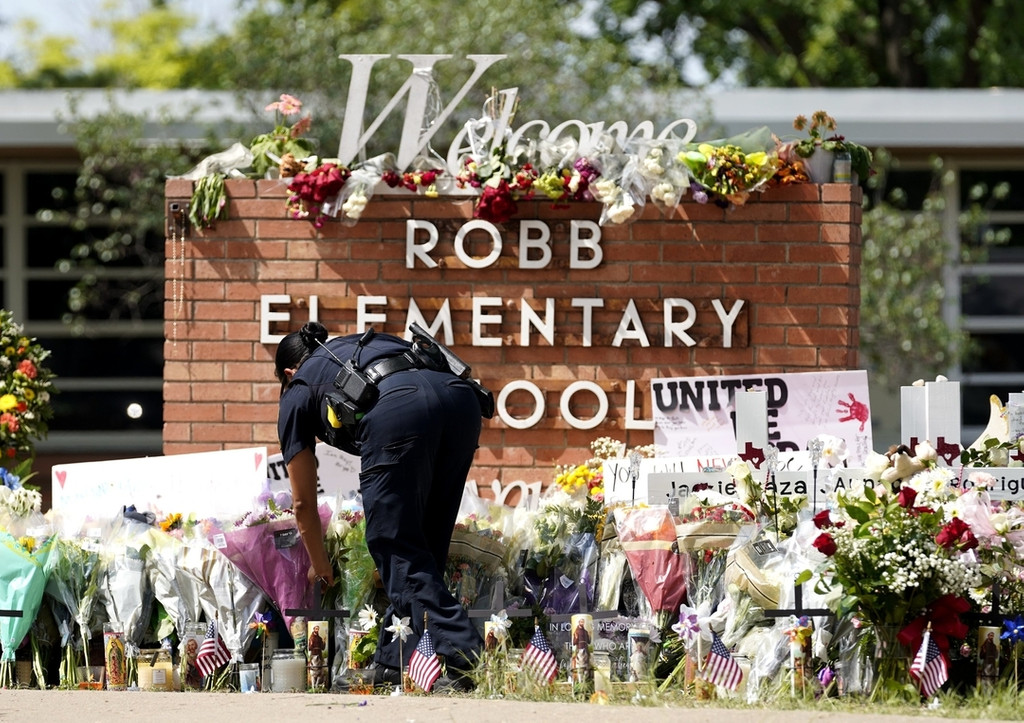 ARCHIV - 27.05.2022, USA, Uvalde: Eine Polizistin legt Blumen vor der Robb Elementary School nieder.