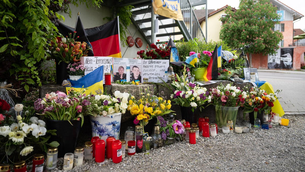 ARCHIV - 02.05.2024, Bayern, Murnau: Neben dem Einkaufszentrum an dem am 27.04.2024 zwei Männer aus der Ukraine getötet worden sind, wurden Blumen niedergelegt. Die beiden ukrainischen Soldaten im Alter von 23 und 36 Jahren waren zur medizinischen Behandlung und Rehabilitation in der Region. (zu dpa: «Zwei Ukrainer in Murnau getötet - Ermittler suchen wichtige Zeugin») Foto: Lukas Barth/dpa +++ dpa-Bildfunk +++