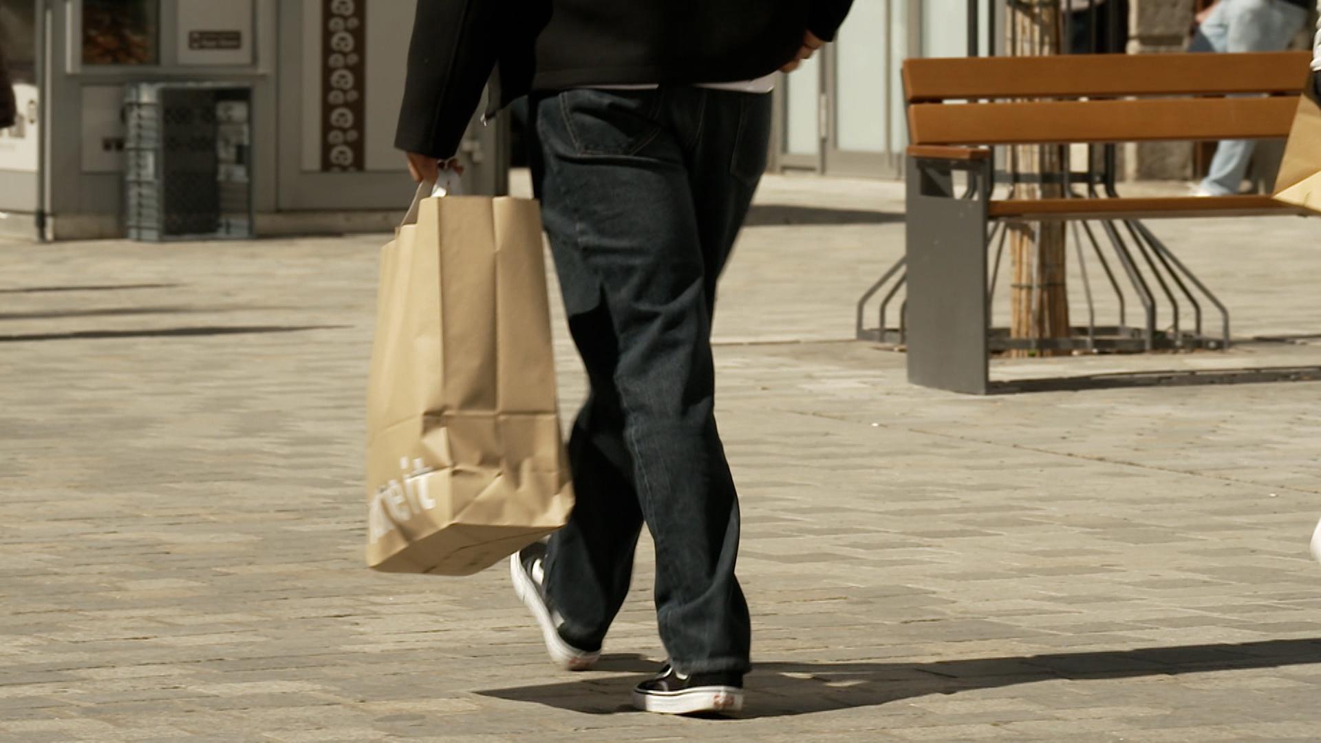 Eine Person ist mit einer Einkaufstausche unterwegs.