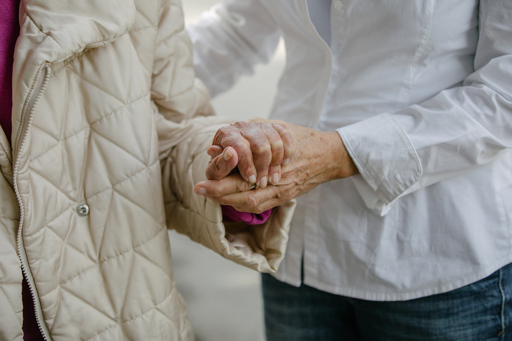 Eine Pflegerin hilft einer Seniorin (Symbolbild)