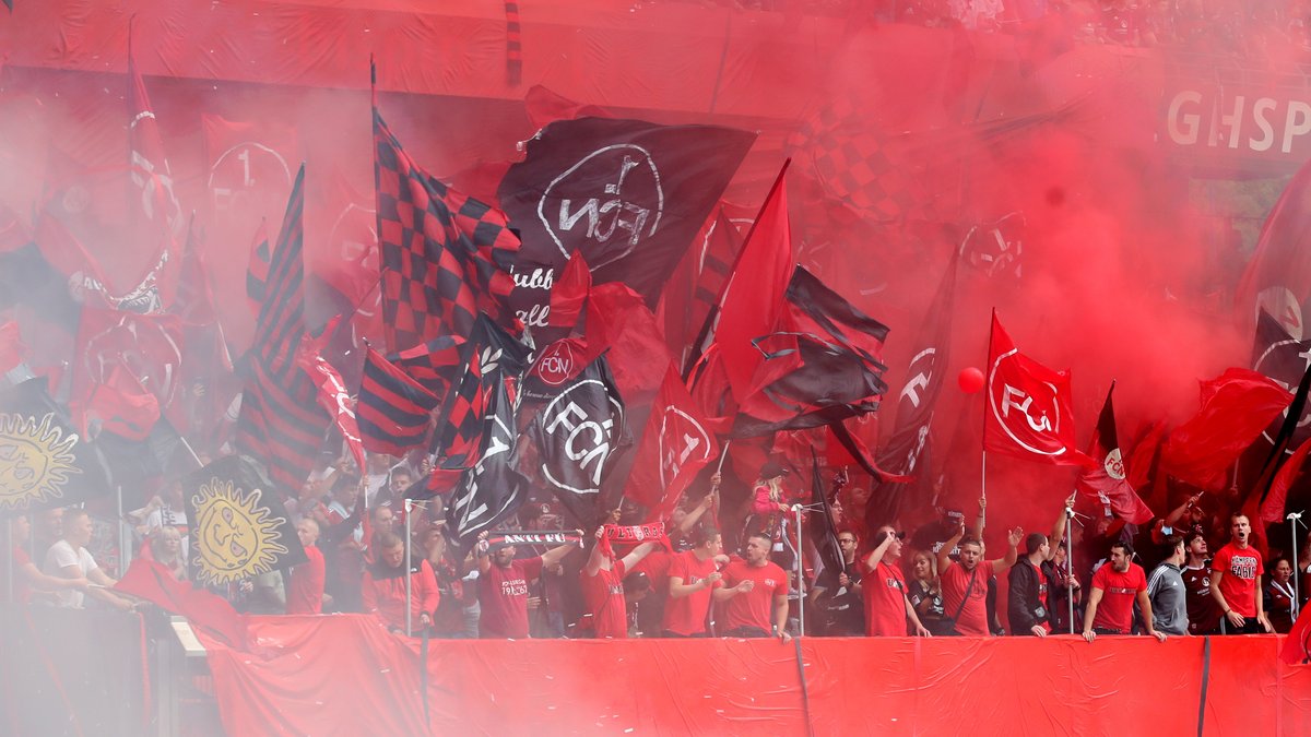Fans des 1. FC Nürnberg schwenken im Max-Morlock-Stadion Fahnen und sind in rot-schwarzen Rauch gehüllt.