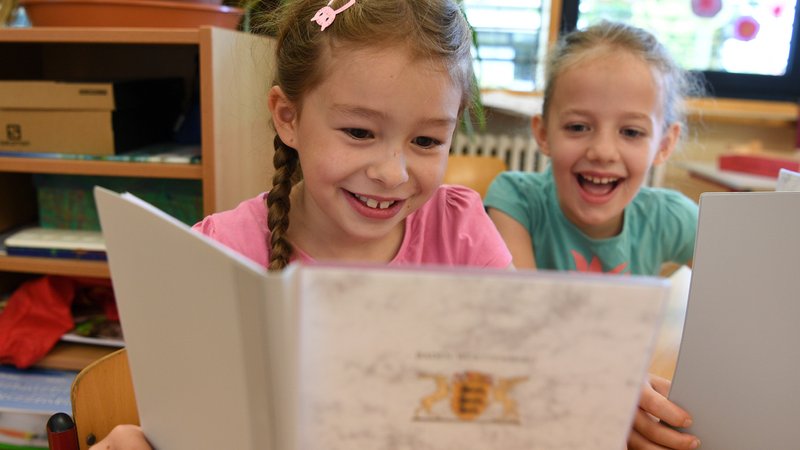 Zwei Mädchen schauen lächeln in ihre Zeugnisse. | Bild: picture alliance/dpa | Felix Kästle Zwei Mädchen schauen lächeln in ihre Zeugnisse.