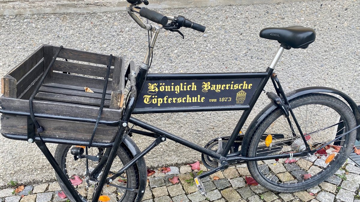 Auf einem alten Fahrrad steht "Königlich Bayerische Töpferschule von 1873"