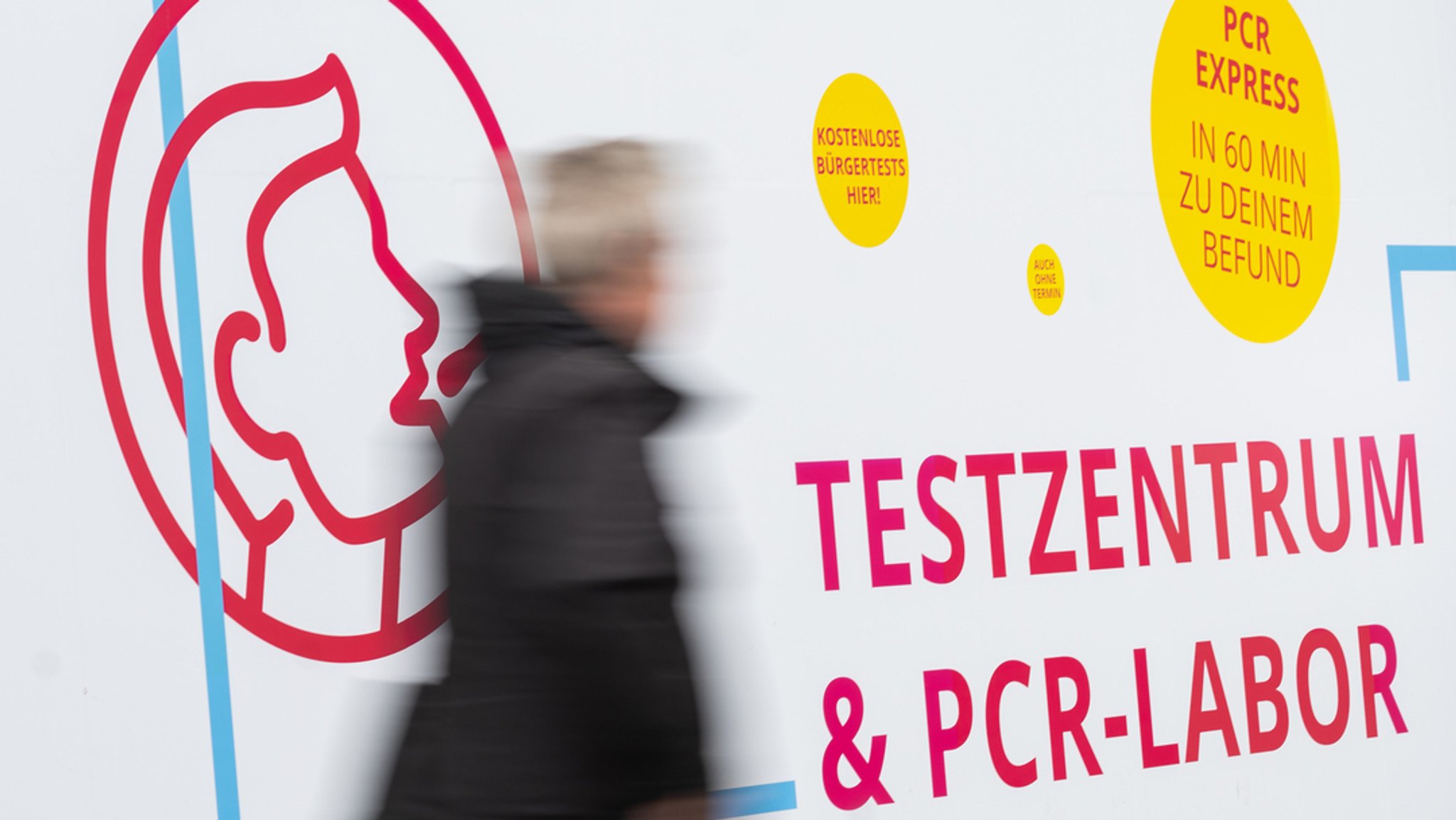 Mann läuft an Werbeplakat für Testzentrum vorbei