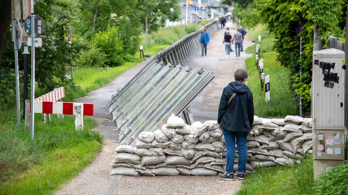 In Regensburg ist ein Uferweg mit Sandsäcken und einer mobilen Hochwasser-Schutzwand gesichert.