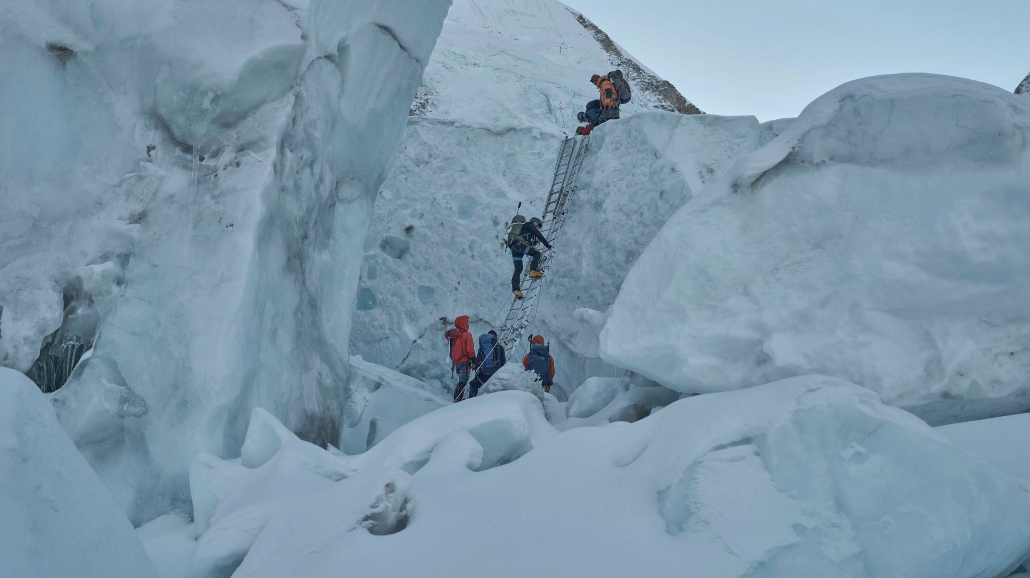(Archivbild) Bergsteiger klettern über eine Leiter eine Eiswand hinauf.