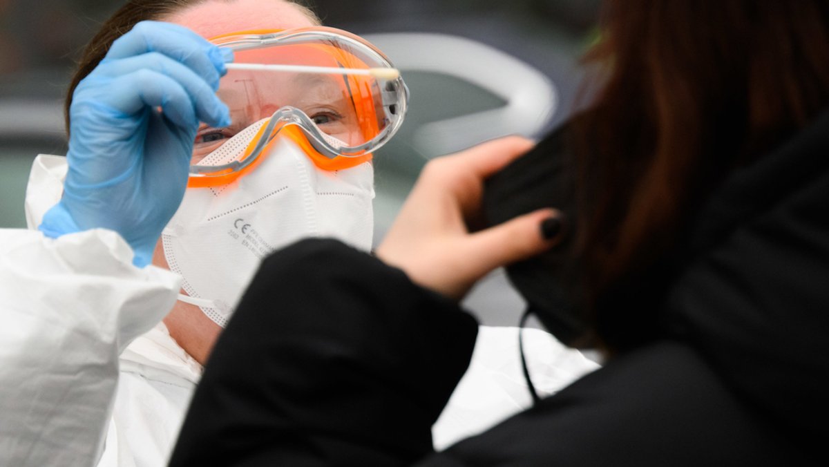 Eine Hausärztin nimmt einen Abstrich von einer Patientin für einen PCR-Test auf das Corona-Virus vor einer Arztpraxis