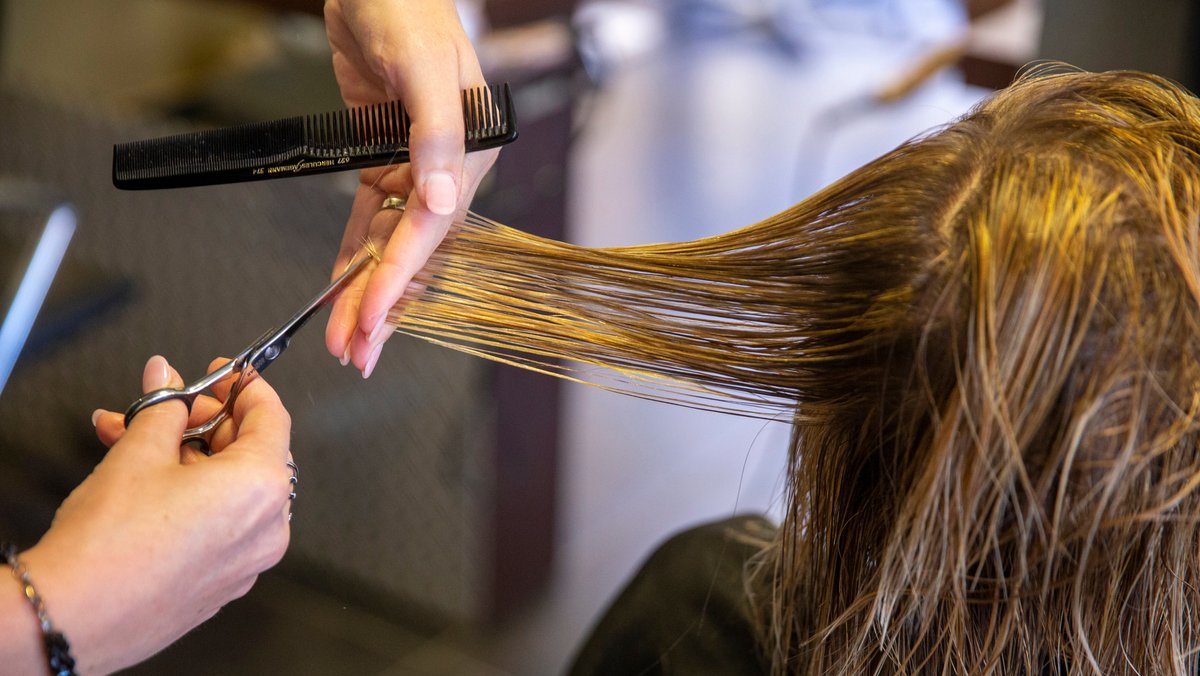 Eine Friseurin in Belgien schneidet einer Kundin die Haare