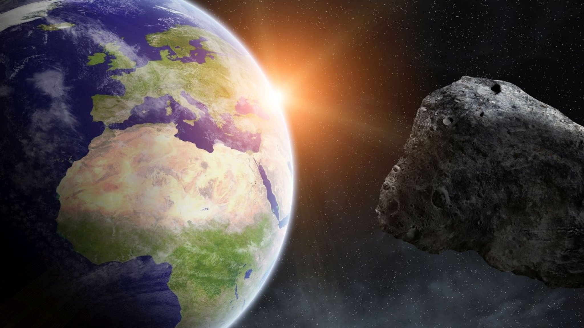 Künstlerische Darstellung: Asteroid fliegt an Erde vorbei. Tausende Asteroiden kreisen um die Sonne - und hin und wieder kommt einer auch in die Nähe der Erde.