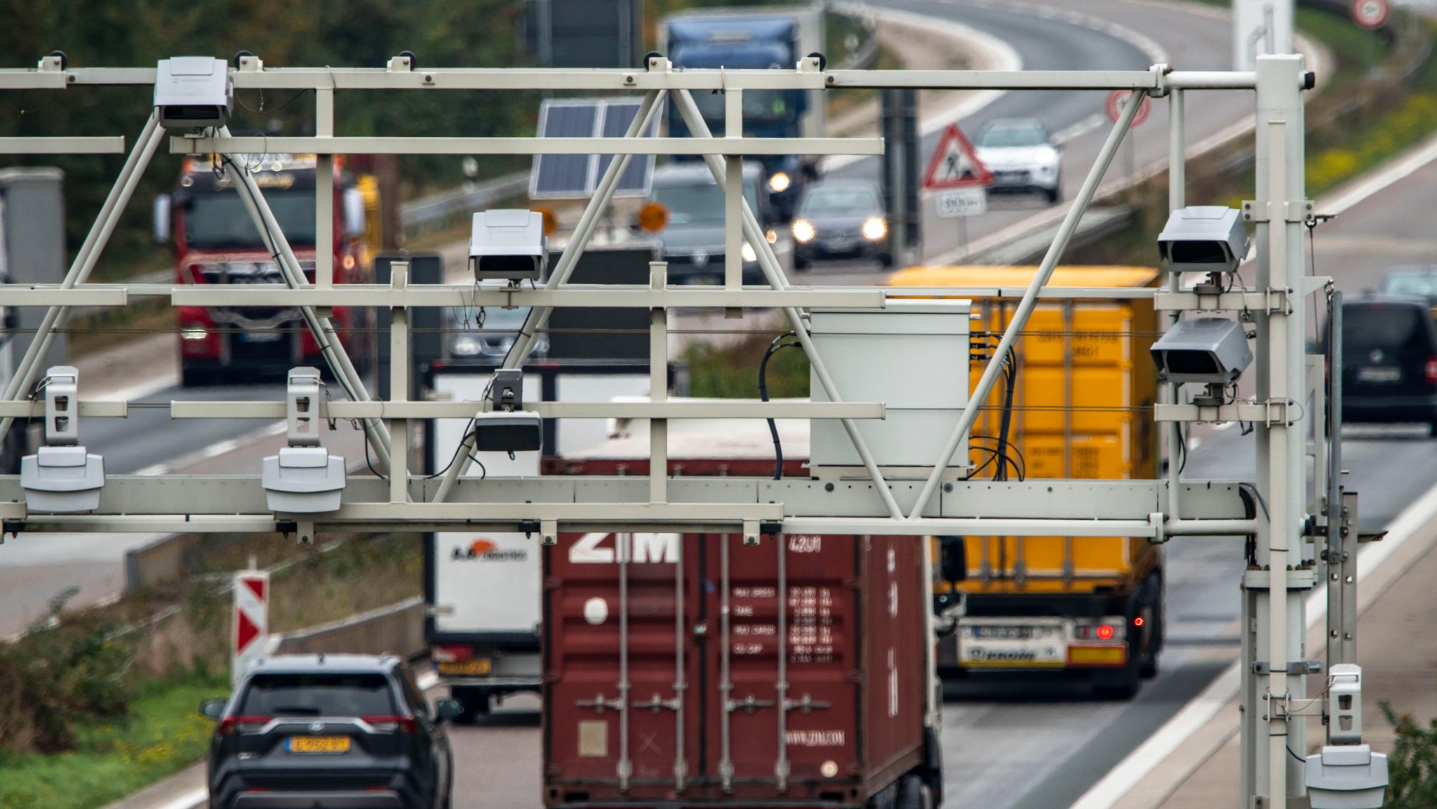 Lastwagen fahren auf der Autobahn unter einer Maut-Kontrollstation hindurch.