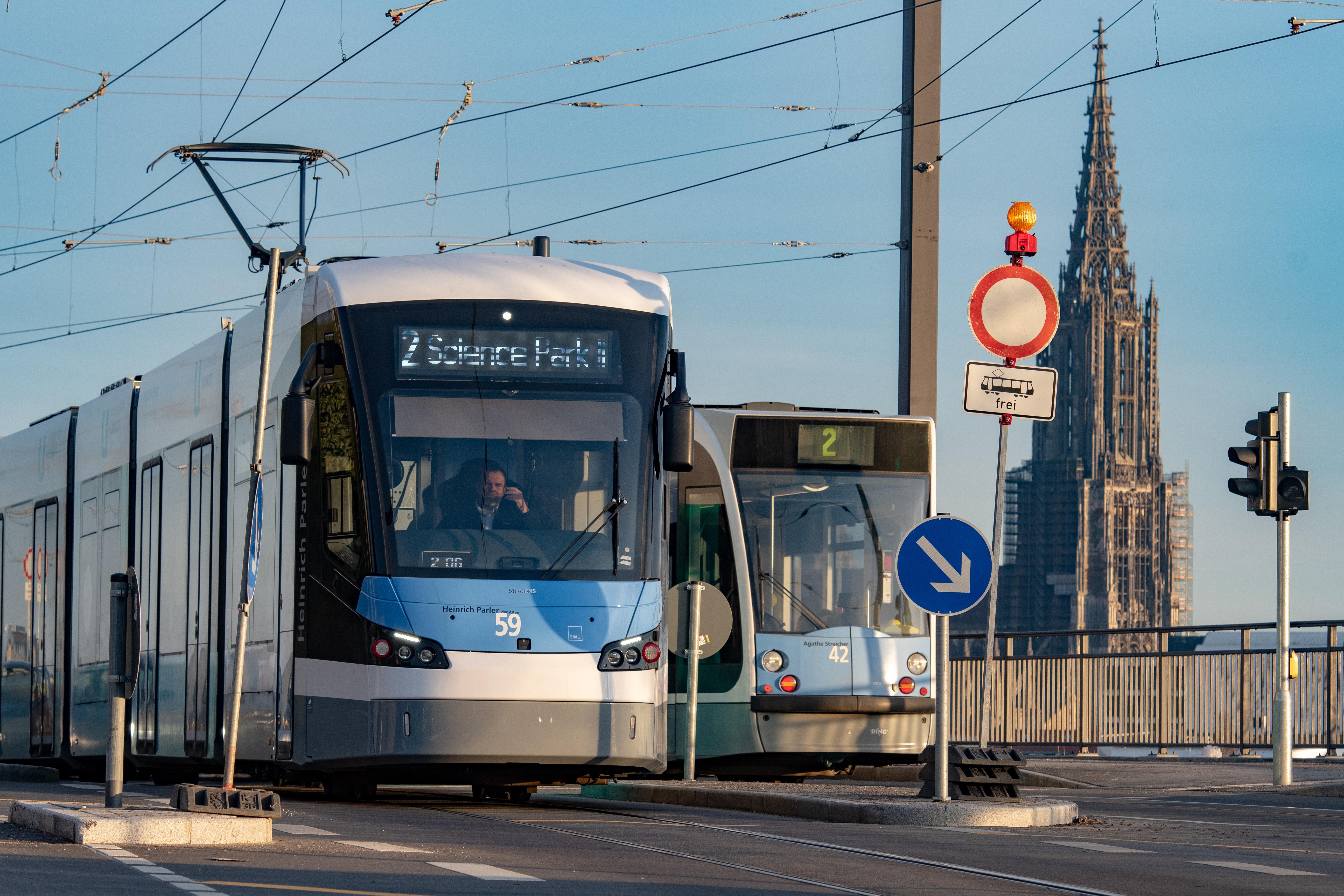 Zwei Straßenbahnen begegnen sich, im Hintergrund ist das Ulmer Münster.