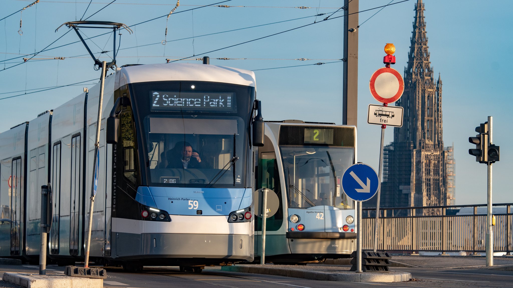 Zwei Straßenbahnen begegnen sich, im Hintergrund ist das Ulmer Münster.