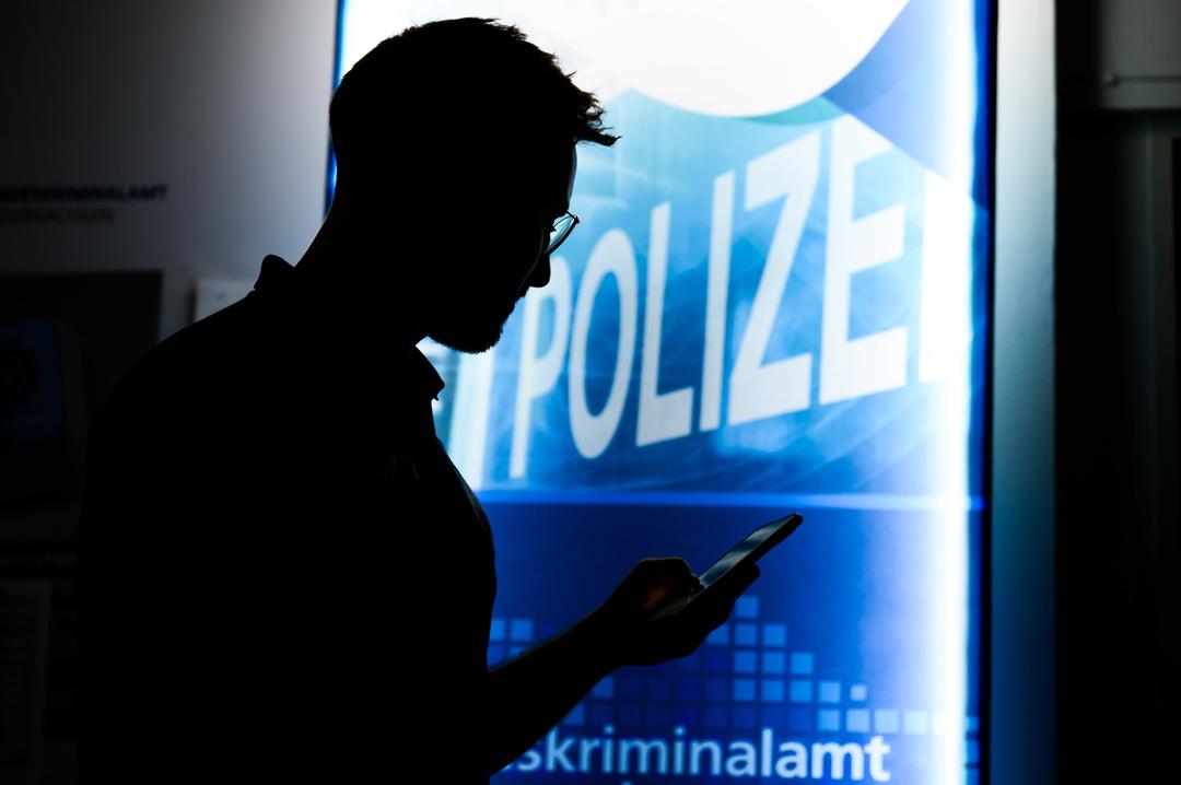 Ein Polizist steht mit einem Smartphone in der Präventionsstelle Cyberkriminalität im Landeskriminalamt Niedersachsen (gestellte Szene) 
