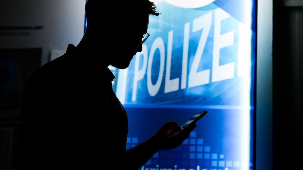 Ein Polizist steht mit einem Smartphone in der Präventionsstelle Cyberkriminalität im Landeskriminalamt Niedersachsen (gestellte Szene) 