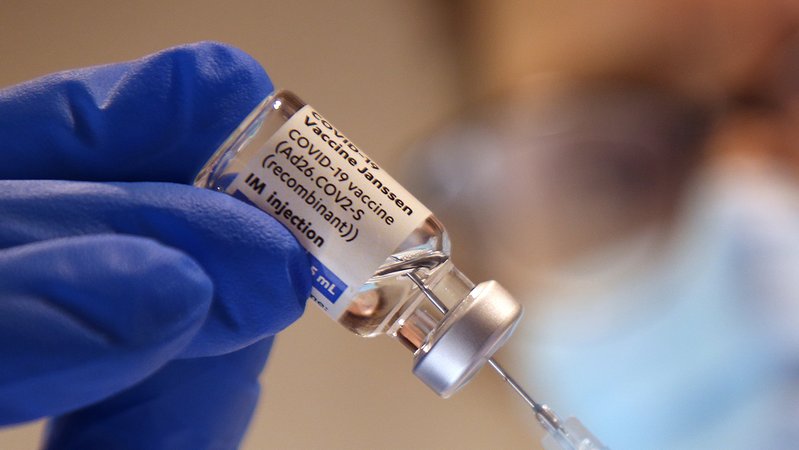 Hand im Handschuh mit Covid-19-Impfstoff-Ampulle