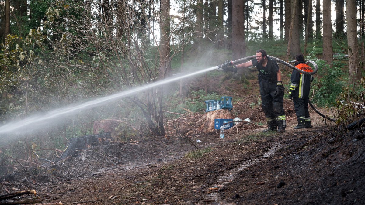 Einsatzkräfte der Feuerwehr löschen den Waldboden. Mehrere Hektar eines Waldgebiets an der Grenze von Bayern und Thüringen waren am Dienstag in Brand geraten.