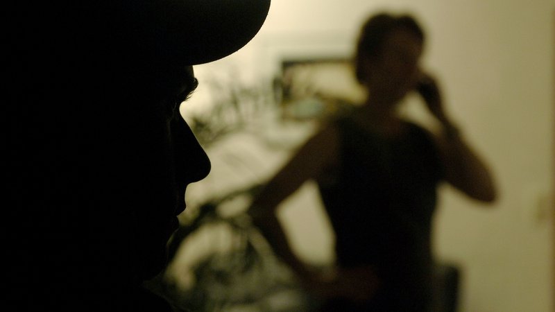 Eine im Schatten stehende, telefonierende Frau wird von einem Mann beobachtet. | Bild: picture-alliance / Frank Kleefeldt Eine im Schatten stehende, telefonierende Frau wird von einem Mann beobachtet.