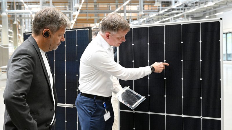 Gunter Erfurt (r), Vorstandsvorsitzender der Meyer Burger Technology AG, erklärt Bundeswirtschaftsminister Robert Habeck (Bündnis 90/Die Grünen) bei einem Unternehmensbesuch vorigen Sommer die Solarpaneele. 