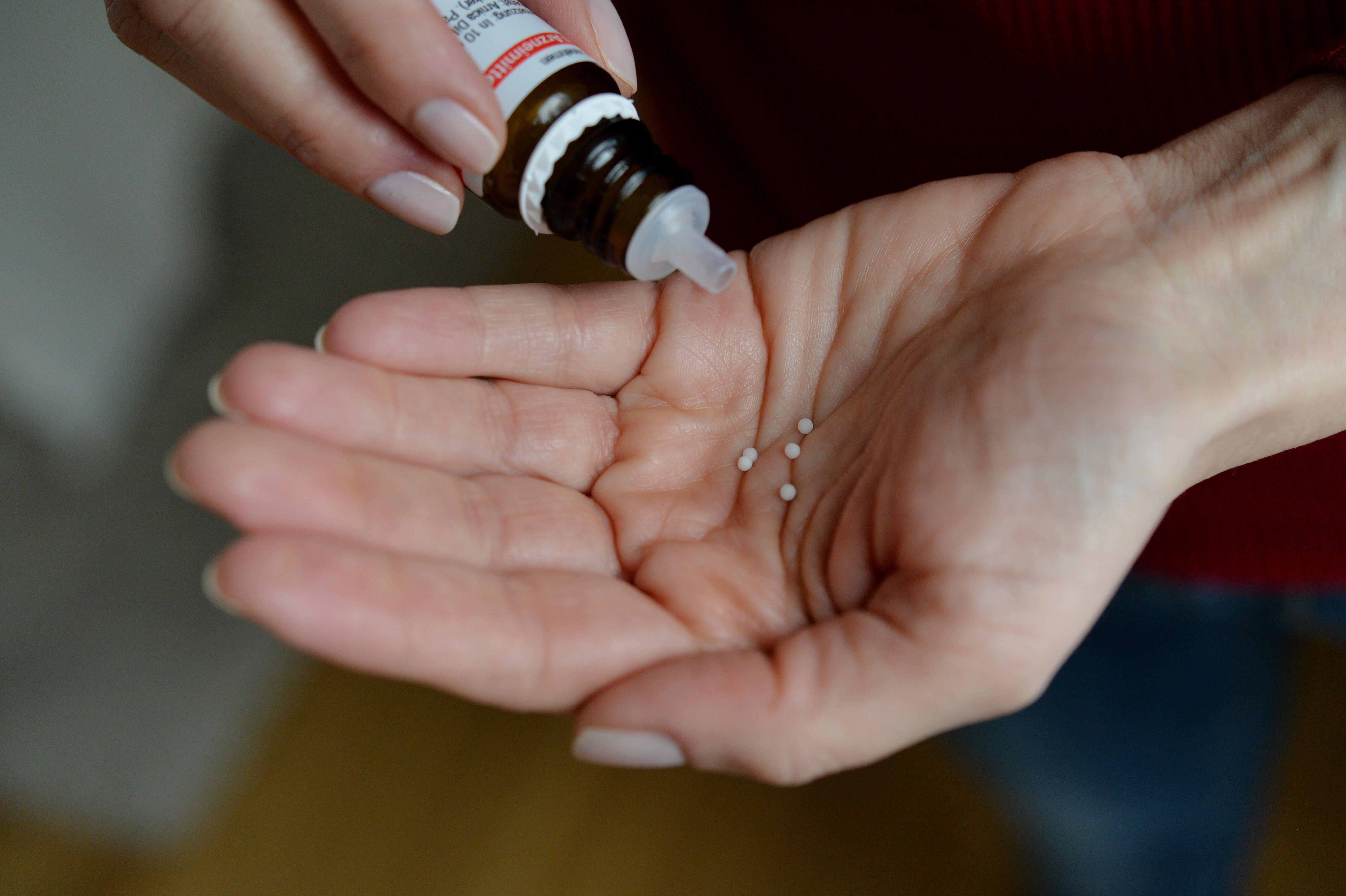 Eine Frau schüttet sich Globuli auf die Hand.