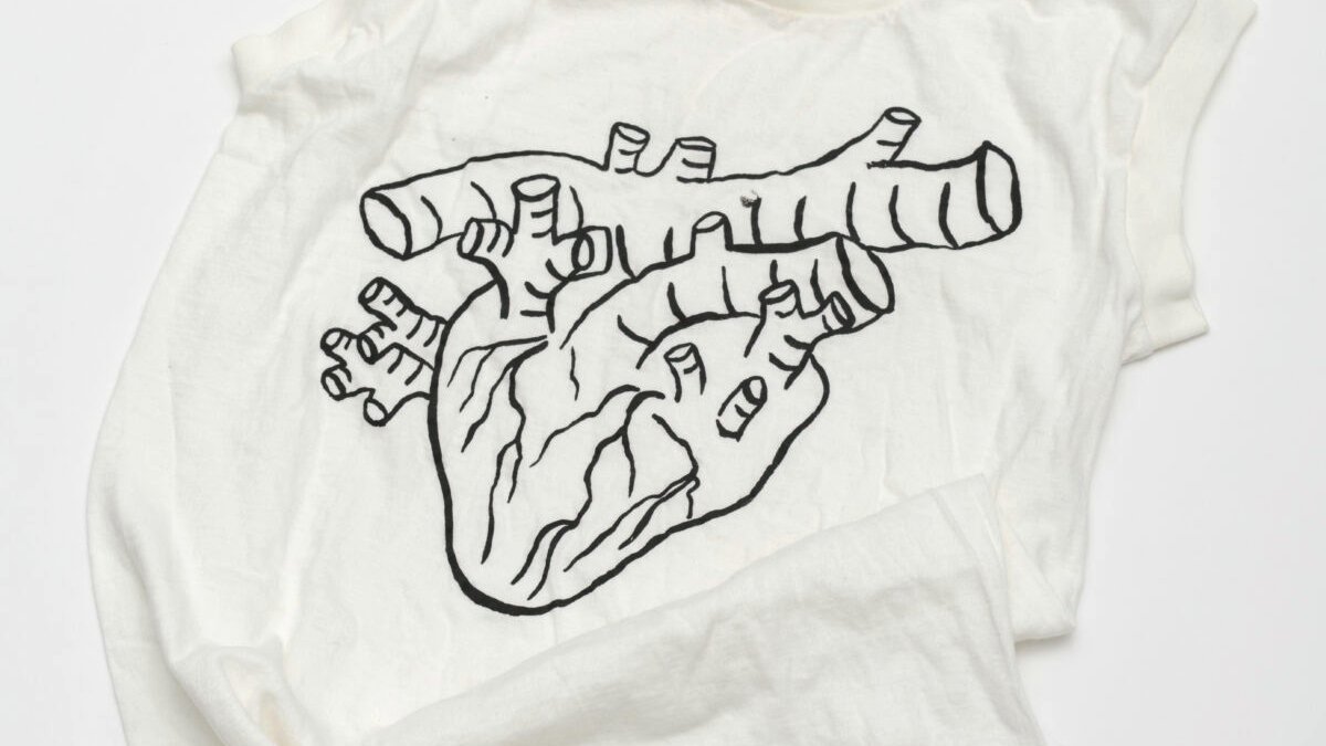 Auf einem weißen T-Shirt ist in grauschwarzen Linien ein menschliches Herz abgebildet