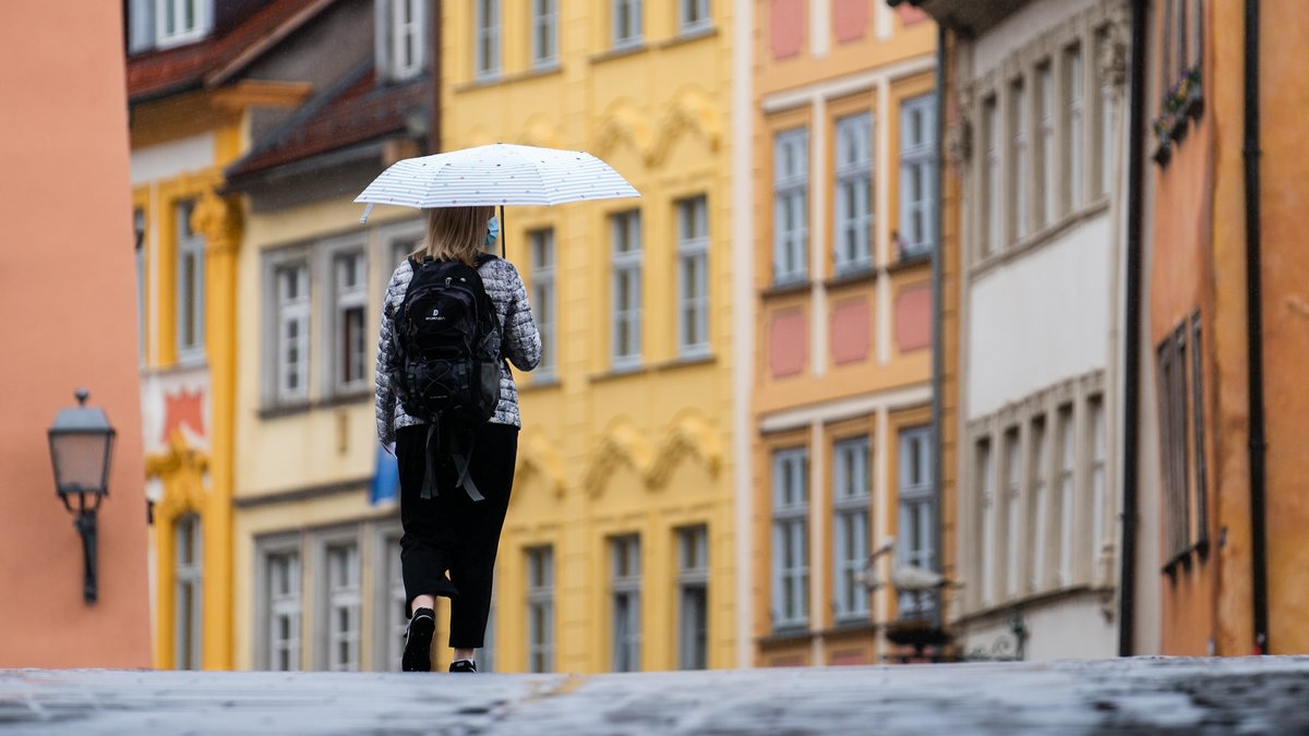 Eine Frau geht mit Regenschirm durch die Innenstadt von Bamberg.